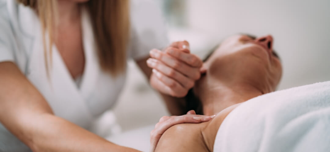 Female therapist massaging woman's neck and shoulder