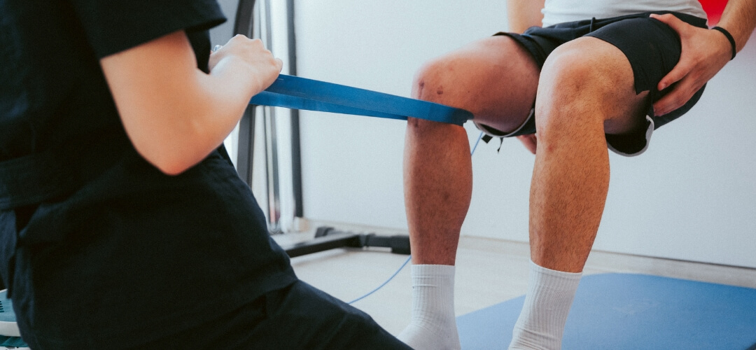 Physiotherapist working on leg with resistance band